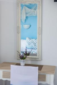 a mirror on a wall with a table and a vase with flowers at Aelia Studios in Koukounaries