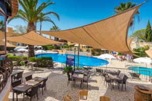 a resort with a pool and tables and chairs at Pestana Palm Gardens in Carvoeiro