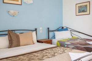 two beds in a room with blue walls at Aelia Studios in Koukounaries