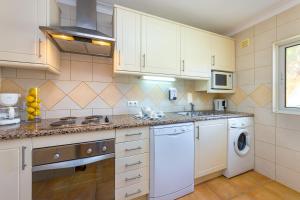 a kitchen with white cabinets and a sink and a dishwasher at Pestana Palm Gardens in Carvoeiro