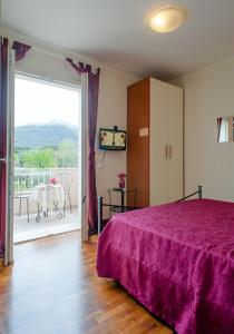 a bedroom with a bed with a purple bedspread at B&B Alle Tre Rose in Montignoso