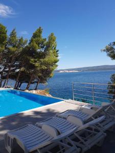 een zwembad met ligstoelen naast het water bij Villa Charlotte in Omiš