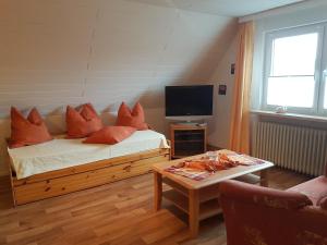 a bedroom with a bed with orange pillows and a tv at Dat Inselhuus in Norden