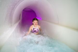 Finlandia Hotel Imatran Kylpylä Spa في إيماترا: بنت صغيرة في زحليقة مائية أرجوانية