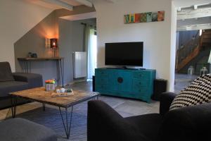uma sala de estar com televisão numa cómoda com mesa em Les Hauts de Crupet em Maillen