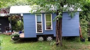 una casita azul estacionada junto a un árbol en Schaferwagen en Kassel