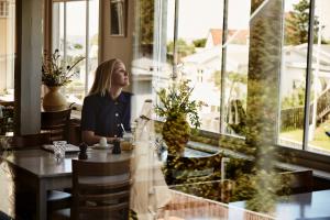 a woman sitting at a table in a restaurant at Tisvildeleje Strandhotel in Tisvilde