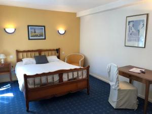 Una habitación de hotel con una cama, una mesa y un escritorio. en Hôtel Villa Du Parc, en Nevers