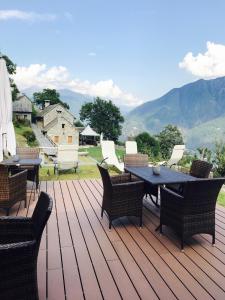 a deck with a table and chairs and mountains at Agriturismo La Tensa in Domodossola