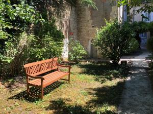 um banco de madeira sentado na relva ao lado de um edifício em Hôtel Villa Du Parc em Nevers