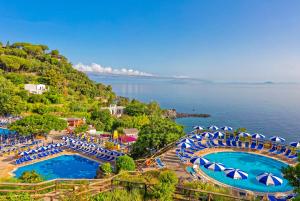 an aerial view of two pools with umbrellas and the water at Hotel Oasi Castiglione in Casamicciola Terme