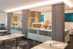 a restaurant with tables and shelves with food on display at Astoria Suite Hotel in Rimini