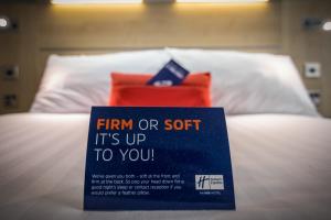 un cartel sentado en la parte superior de una cama con una almohada en Holiday Inn Express Kettering, an IHG Hotel en Kettering