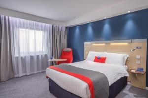 um quarto de hotel com uma cama e uma cadeira vermelha em Holiday Inn Express Kettering, an IHG Hotel em Kettering