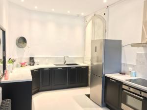 uma cozinha com armários pretos e um frigorífico de aço inoxidável em La Charuel em Épernay