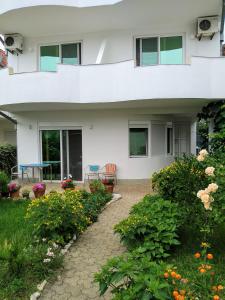 a white house with a patio and flowers at Apartments and Rooms Mila in Ulcinj