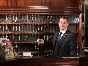 a man in a suit standing behind a counter at Excelsior Hotel Ernst am Dom in Cologne