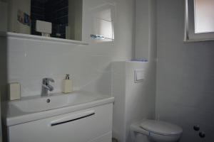 a white bathroom with a sink and a toilet at Apartmani Babić in Sevid