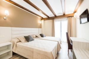 Una habitación de hotel con dos camas y un televisor. en Hotel Atiana, en Albarracín