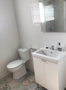 a white bathroom with a toilet and a sink at Villa pilonga in Dos Hermanas