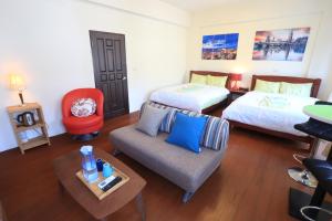 Cette chambre comprend deux lits, un canapé et une table. dans l'établissement Downshifters House, à Tongluo