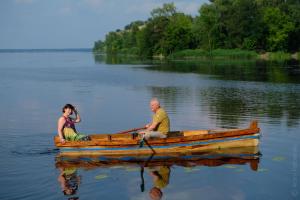 two people sitting in a wooden boat on a lake at Hotel Black Cube in Tripolʼye