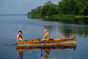2 personnes assises dans un bateau en bois sur un lac dans l'établissement Hotel Black Cube, à Tripolʼye