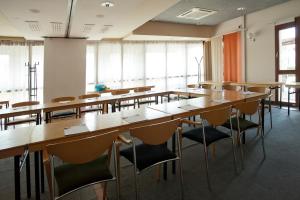 a classroom with wooden tables and chairs and windows at Hotel Lifestyle in Landshut