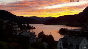 una puesta de sol sobre un lago con casas y montañas en Berge & Laila's Private Apartment, en Førde