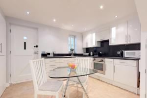 a kitchen with a glass table and white cabinets at Panfield House in Braintree