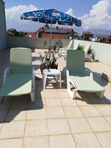 ラブダにあるRuskovi Guest Houseの屋根に椅子2脚、テーブル1台、傘1本