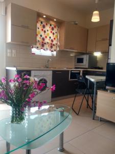 a kitchen with a glass table with a vase of flowers at Bright and cozy apartment near the city center in Zakynthos Town