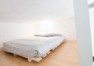 a bed in a white room with a wooden floor at Fairholme Studios in London