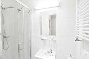 a white bathroom with a shower and a sink at Fairholme Studios in London