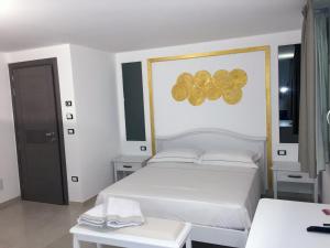 Un dormitorio con una cama blanca con una pintura dorada en la pared en B&B Bella Costa - lungomare Porto Cesareo, en Porto Cesareo