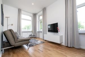 ein weißes Wohnzimmer mit einem TV und einem Stuhl in der Unterkunft Freiburg Apartments Friedrichring in Freiburg im Breisgau