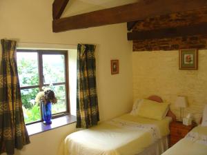 MertonにあるStable Cottageのベッドルーム1室(ベッド2台付)、花瓶のある窓が備わります。