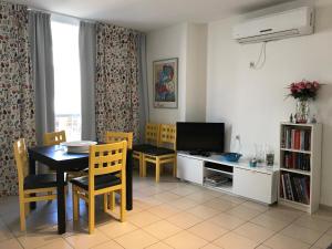 uma sala de estar com uma mesa de jantar e uma televisão em Lucy em Netanya