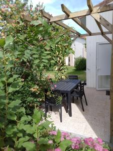 une table et des chaises noires sous une pergola en bois dans l'établissement Pescalis Résidence Les Maisons du Lac, à Moncoutant