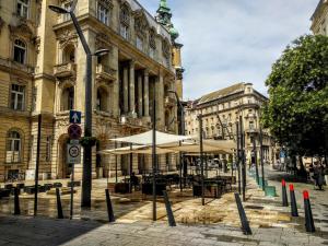 a street with tables and umbrellas in front of a building at Christoph's Central Apartment in Budapest