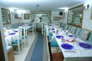 una sala da pranzo con tavoli bianchi e sedie blu di Hotel Kaduku a Shkodër