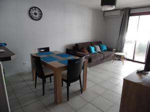 sala de estar con mesa, sillas y sofá en Airport Appart en Sainte-Clotilde