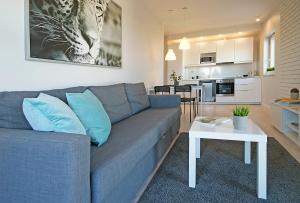 ein Wohnzimmer mit einem blauen Sofa und einer Küche in der Unterkunft IRS ROYAL APARTMENTS Apartamenty IRS Albatros in Danzig