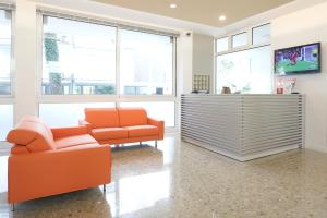 a living room with orange furniture and windows at Hotel Meubl&egrave; Zenith in Lignano Sabbiadoro
