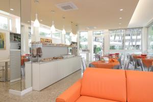 un restaurant avec des meubles orange, des tables et des fenêtres dans l'établissement Hotel Meublè Zenith, à Lignano Sabbiadoro