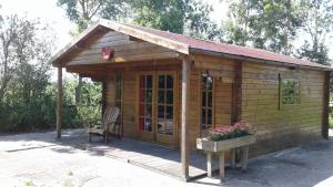 een kleine houten hut met een bank en bloemen bij blokhut us Mem in Boazum