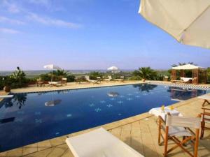 a large swimming pool with chairs and an umbrella at Borgo Valle Rita in Ginosa Marina