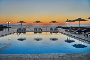 a pool with tables and chairs and umbrellas at Nanakis Beach Apartments in Stavros