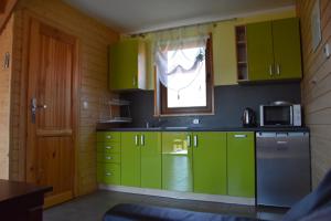 kuchnia z zielonymi szafkami i oknem w obiekcie Domki na Różanej 2 w Rowach
