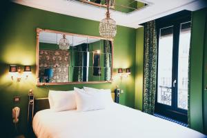 a bedroom with green walls and a bed with a mirror at La Mondaine in Paris